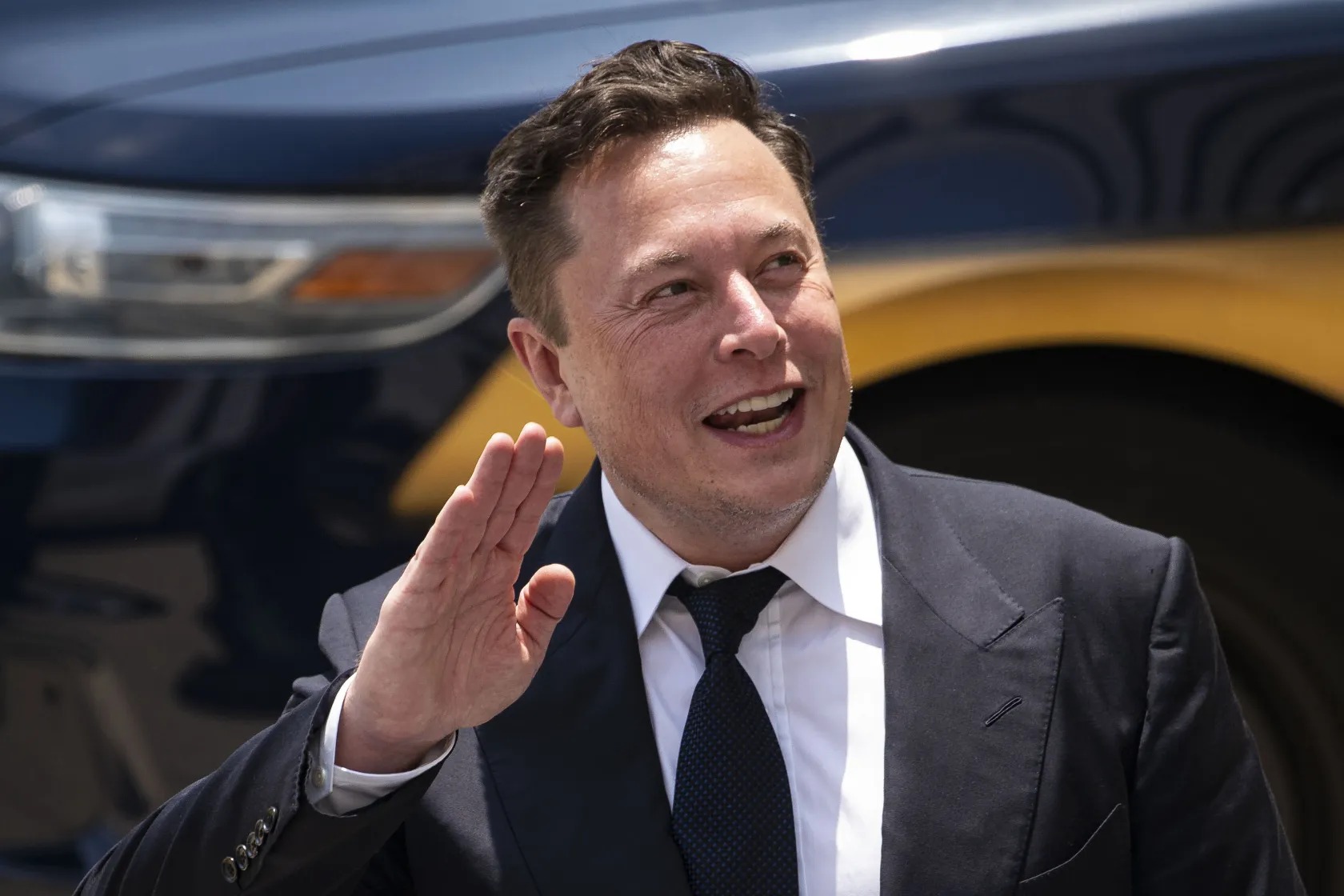 2022-11-elon-musk-black-suit-smile-hand-638bb8ecef7c1a7ce6f285f4_11zon