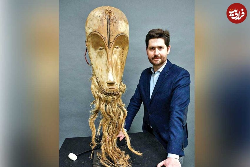 auctioneer_jean-christophe_giuseppi_poses_next_to_a_ngil_mask_of_the_fang_people_of_gabon_-_worth_an_estimated_300000-400000_euros_up_for_auction_on_march_26_2022._afp
