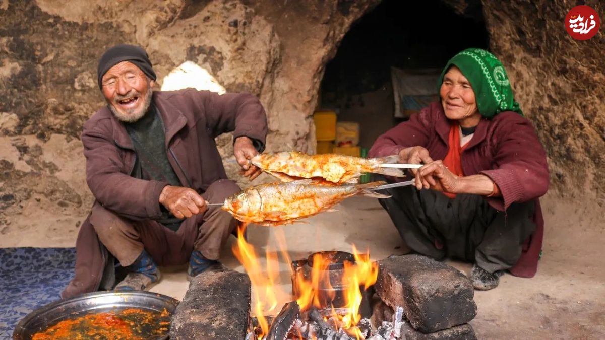 (ویدئو) نمایی دیدنی از کباب کردن ماهی روی زغال توسط یک زوج غارنشین افغان