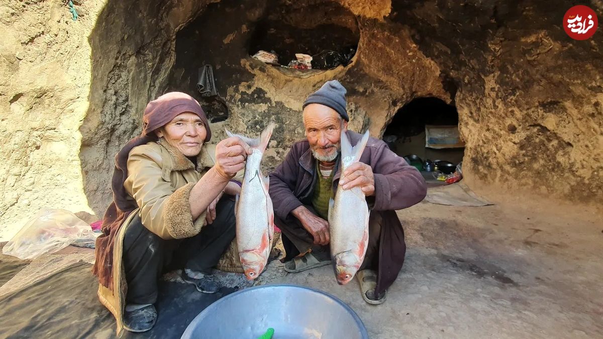 (ویدئو) سرخ کردن دو ماهی آزاد روی ساج توسط زوج مسن غارنشین افغانستانی