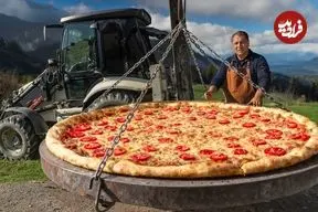 ببینید| غذای روستایی در آذربایجان؛ پخت یک پیتزای غول پیکر در فضای باز و حمل آن با بیل مکانیکی!