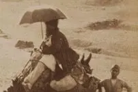 عکس| سفر زمان؛ زن و مرد کجاوه‌سوار و مردی با چتر در حال سفر با کاروان؛ بیش از 100 سال قبل