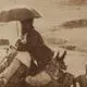 عکس| سفر زمان؛ زن و مرد کجاوه‌سوار و مردی با چتر در حال سفر با کاروان؛ بیش از 100 سال قبل
